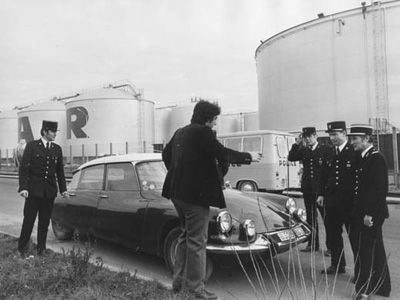 14 января 1974: Водитель объясняется с полицейскими по поводу автомобиля, припаркованного у бензохранилища во Франции. На территории бензохранилищ была усилена охрана на фоне волнений, вспыхнувших из-за отказа ОПЕК продавать нефть западным странам.